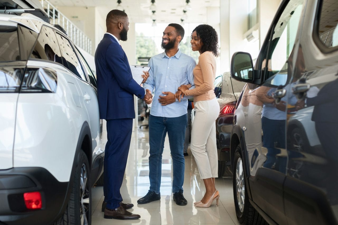 car purchase happy customers couple handshaking with manager in auto salon