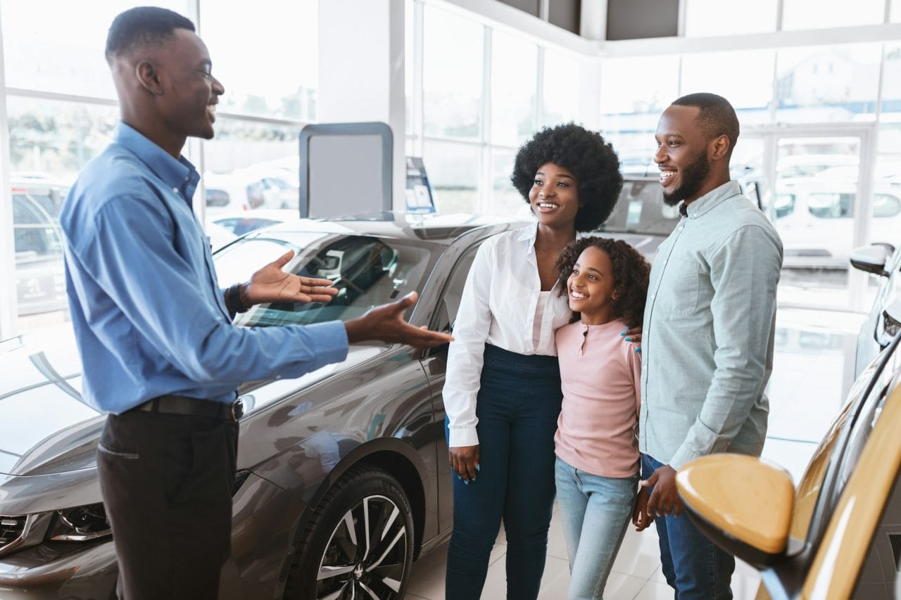 car purchase or rental millennial black family with kid speaking to salesman